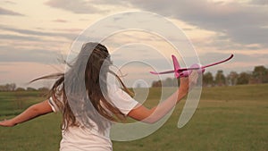 A little girl with long hair plays the illusion of flying with an airplane. The teenager dreams of becoming a pilot and