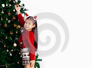 Little girl long hairstyle in red sweater decoring christmas tree at home