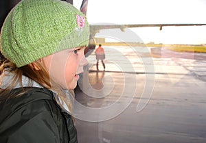 Little girl looking through the airport window.