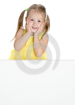 A little girl is looking from behind an empty banner.