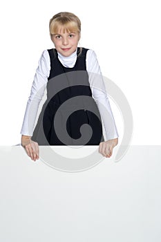 A little girl is looking from behind an empty banner.