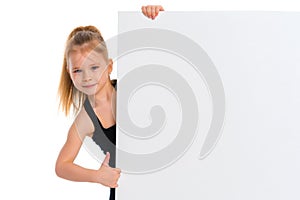 A little girl is looking from behind an empty banner.