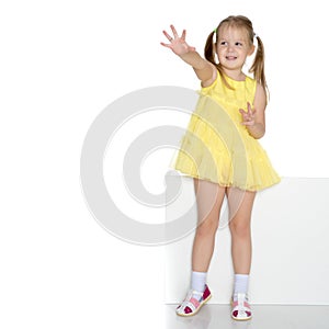 A little girl is looking from behind an empty banner.