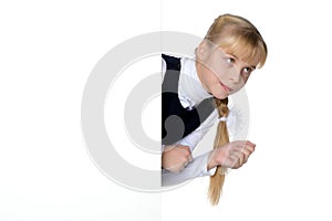 A little girl is looking from behind an empty banner.