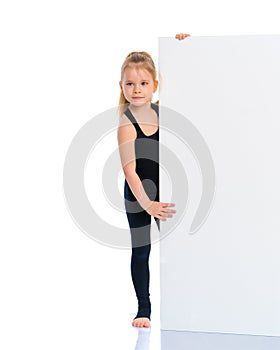 A little girl is looking from behind an empty banner.