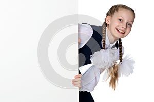 A little girl is looking from behind an empty banner.