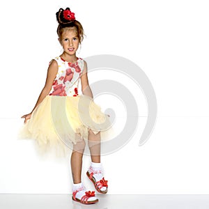 A little girl is looking from behind an empty banner.