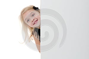 A little girl is looking from behind an empty banner.