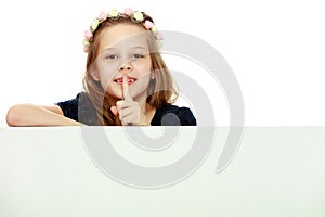 A little girl is looking from behind an empty banner.