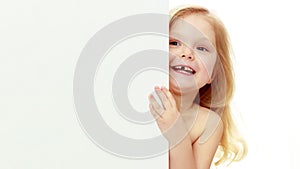 A little girl is looking from behind an empty banner.