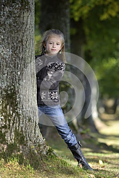 Little girl looking from behind a tree