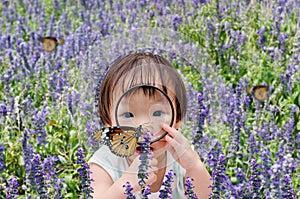 Little girl looking at butterfly with magnifying glass