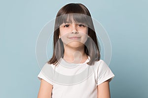 Little girl looking at camera isolated on blue studio background