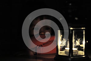 Little girl looking at candle light in lantern