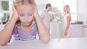 Little girl looking depressed in front of fighting parents