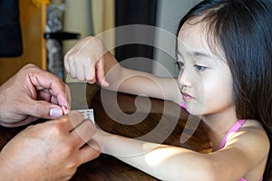 LIttle girl looking at her hand with nail stickers placed by the father at home