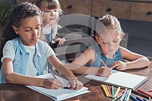 little girl looking how friends drawing pictures with colorful markers