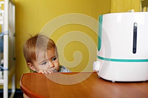 Little girl is looking on a humidifier in bedroom