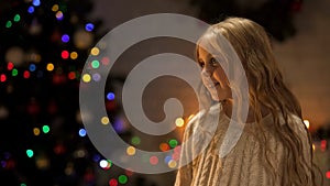 Little girl looking out Santa near glowing Christmas tree, holiday anticipation