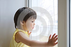 Little girl looking out the window longing for some sunshine. child sitting home at rainy day