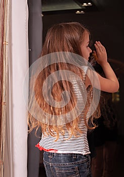 Little girl looking out window while standing on windowsill