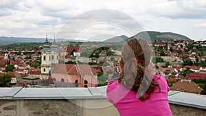 Little girl looking through sightseeing binoculars on old town Eger