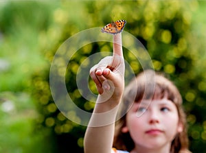 Little girl looks at a butterfly. Aglais urticae L. photo