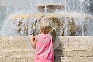 Little girl looks at the fountain. photo
