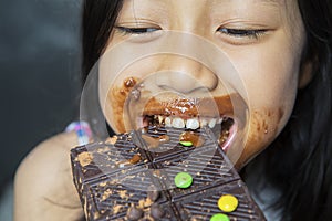 Little girl looks happy while eating chocolate