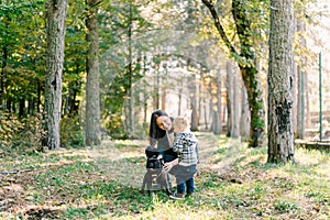 Little girl looks at her mother stroking a dog in the park