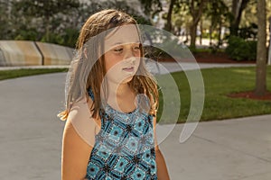A little girl looks with an intense curiosity downward while in the park