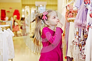 Little girl looks with interest upon dresses