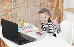 Little girl looks at laptop and learns to draw