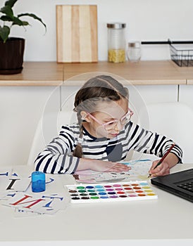 Little girl looks at laptop and learns to draw