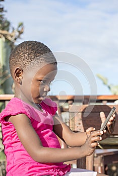 Little Girl Looks at Mobile Phone Screen.
