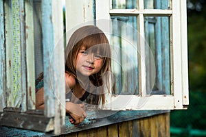 Little girl looks out the window rural house