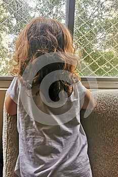 Little girl looks at the rain through the window photo