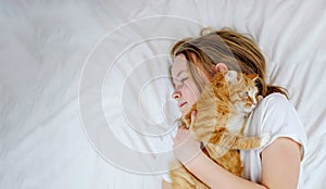 Little girl lying in the bed with her cat. Copy space