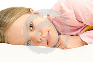 A little girl lying in bed with open eyes