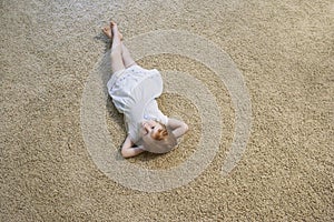 Little Girl Lying On Carpet At Home