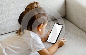 Little Girl Lying On Couch And Using Blank Smartphone With White Screen