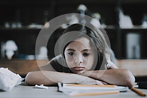 Little Girl Lying at Desk Shows Bored Expression