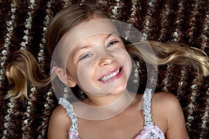 Little girl lying down on a rug and smiling