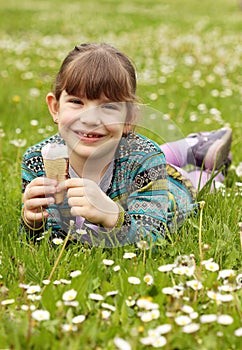 Little girl lying on grass and eat ice cream