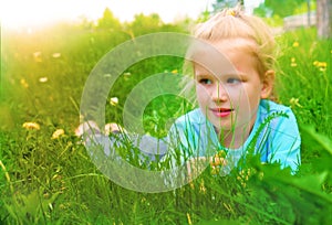 Little girl lying on grass lawn. Summer fun outdoors. Happy child enjoying on grass field and dreaming