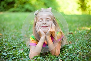 Little girl is lying on the green grass