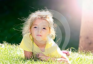 Little girl lying on the green grass.Child outdoor closeup face.