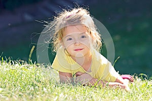 Little girl lying on the green grass.Child outdoor closeup face