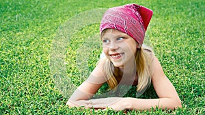 Little girl lying on green grass in the summer park