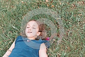 Little girl lying on the green grass on a warm summer day
